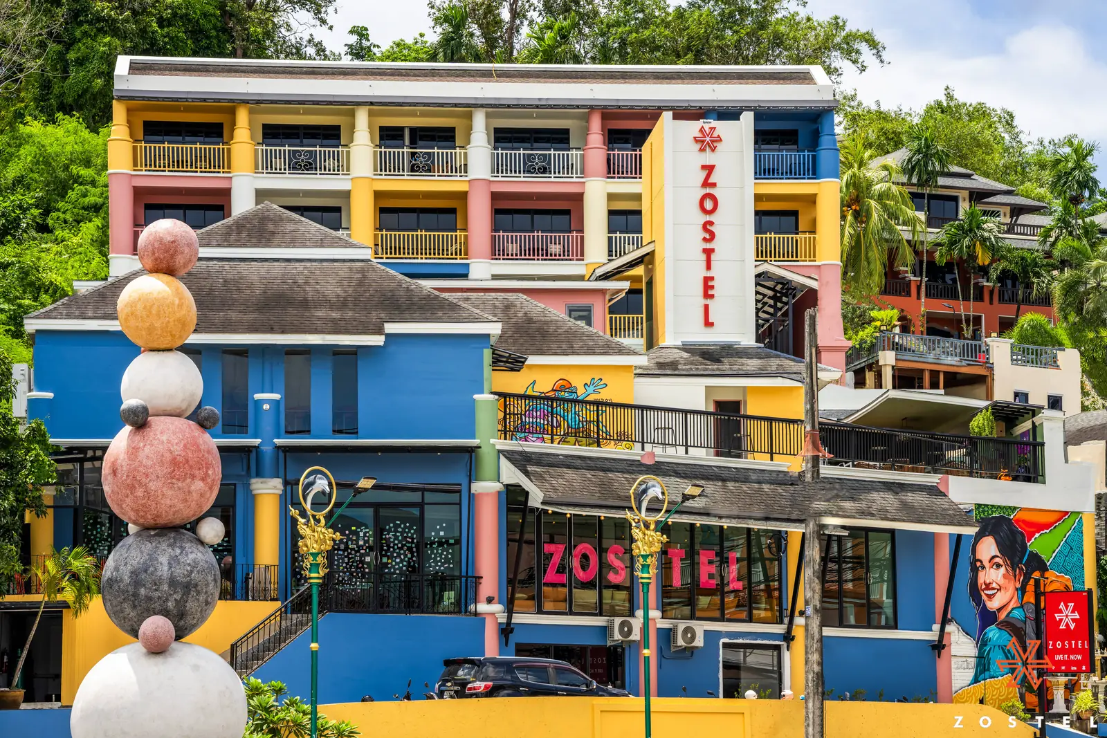 Zostel Phuket from the street: painted facade, signage and a mural portrait on the right wall